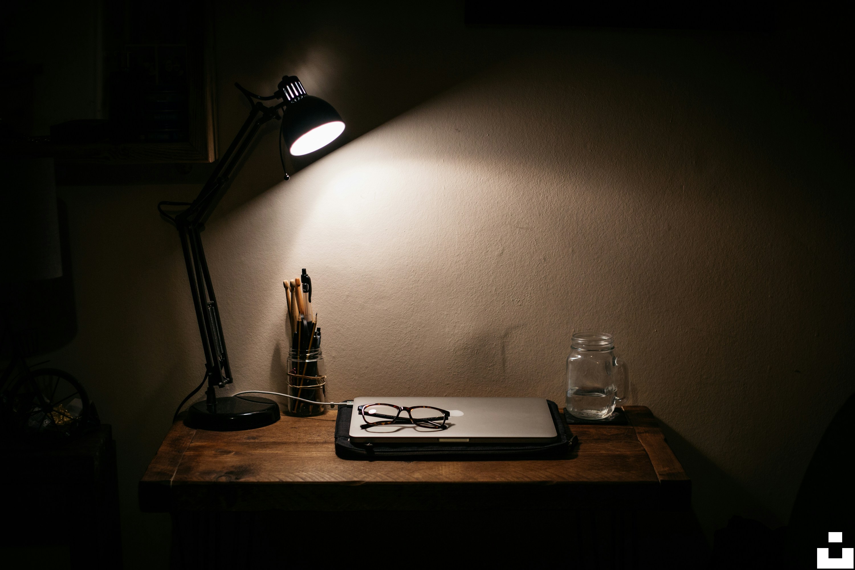 Soft lamp light on a side table with a closed laptop suggesting an evening wind-down space